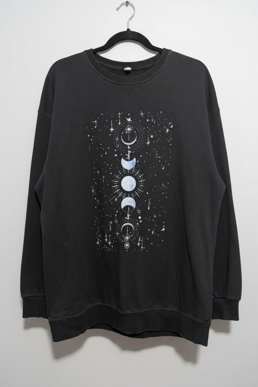 Front view of a faded black oversized crew neck sweatshirt featuring a vertical white graphic print of moon phases.