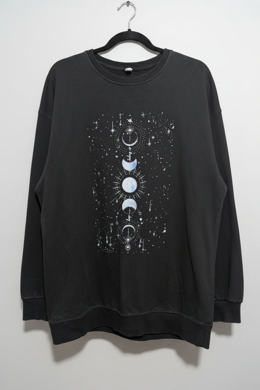 Front view of a faded black oversized crew neck sweatshirt featuring a vertical white graphic print of moon phases.
