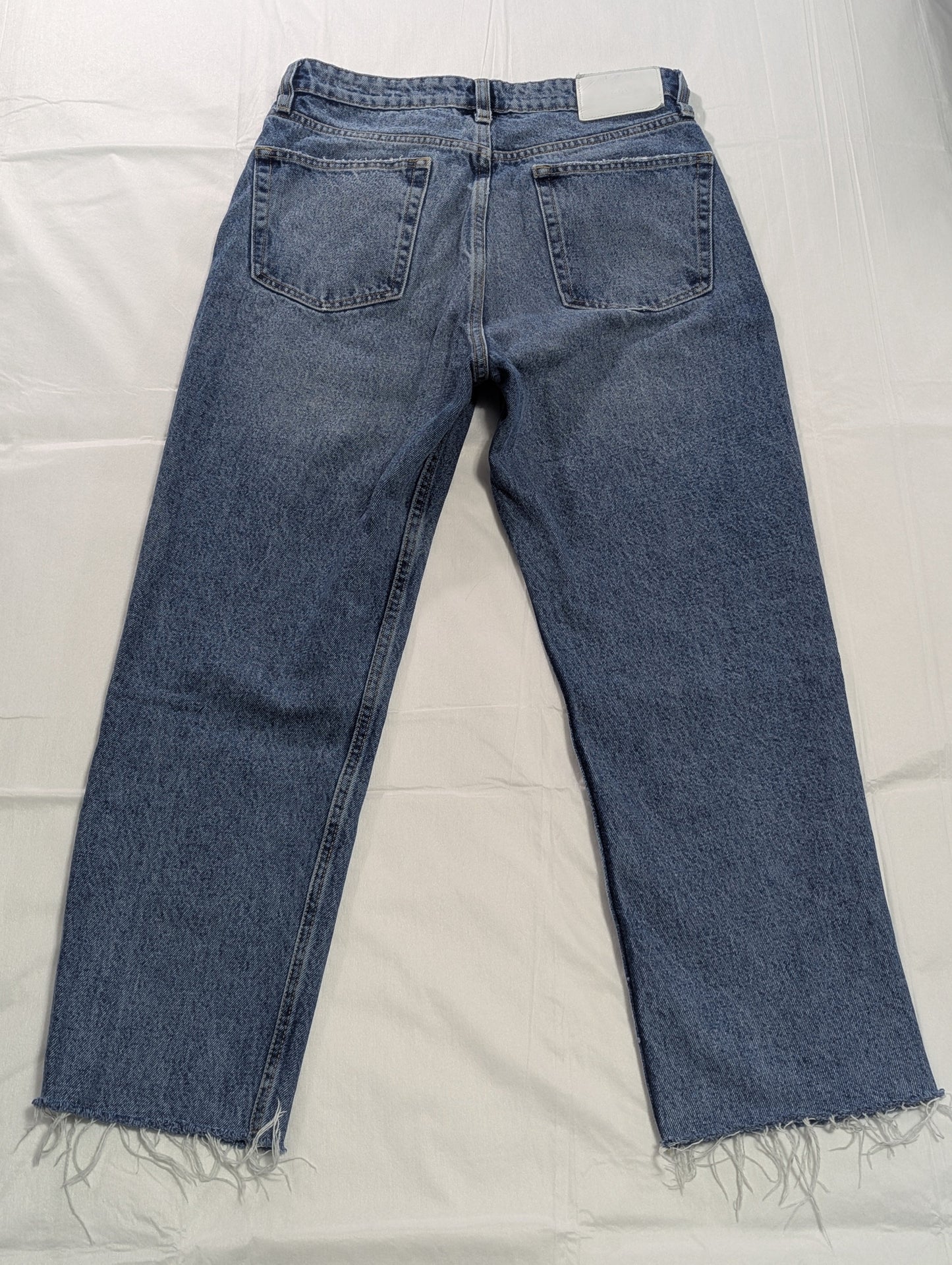 Full-length back view of mid-wash blue Zara high-rise cropped denim jeans with raw frayed hems, displayed flat.